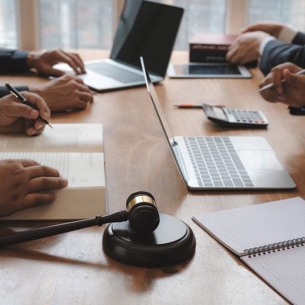 A gavel sits on the table, surrounded by Pain Pros diligently taking notes and typing on laptops during an intense meeting.